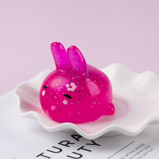 Mochi squishy, Pink glittery rabbit-shaped object on a white dish with a light pink background