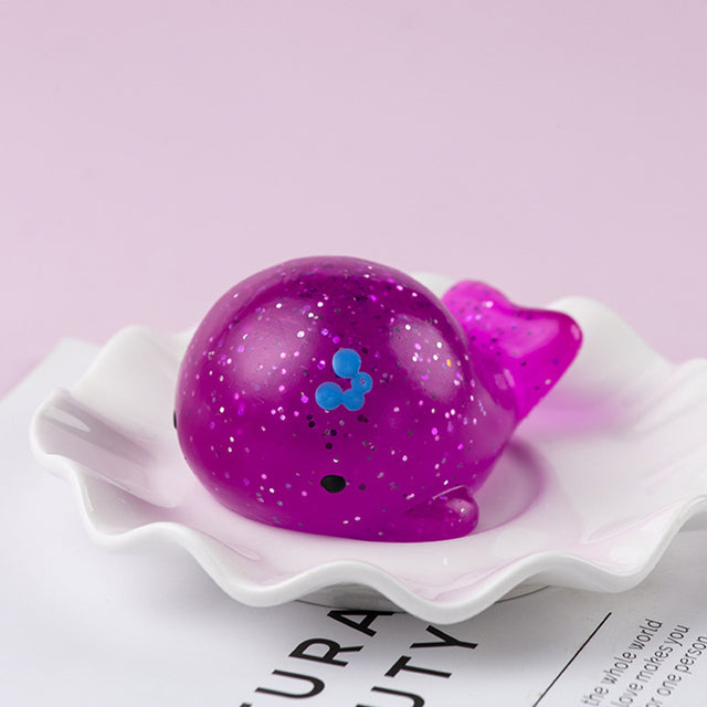 Purple Mochi squishy, Purple glittery whale toy on a white dish with a pink background