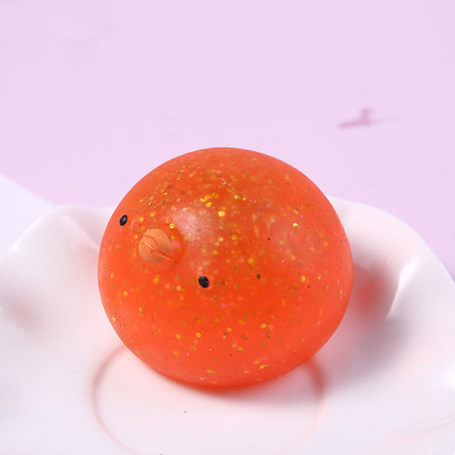 Orange Mochi squishy , Orange textured ball with a small face on a white plate against a light purple background